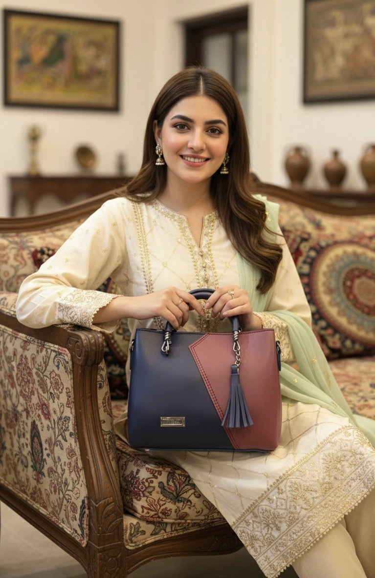 top-handle handbag with a distinctive two-tone color block design and a tassel charm accent 💼