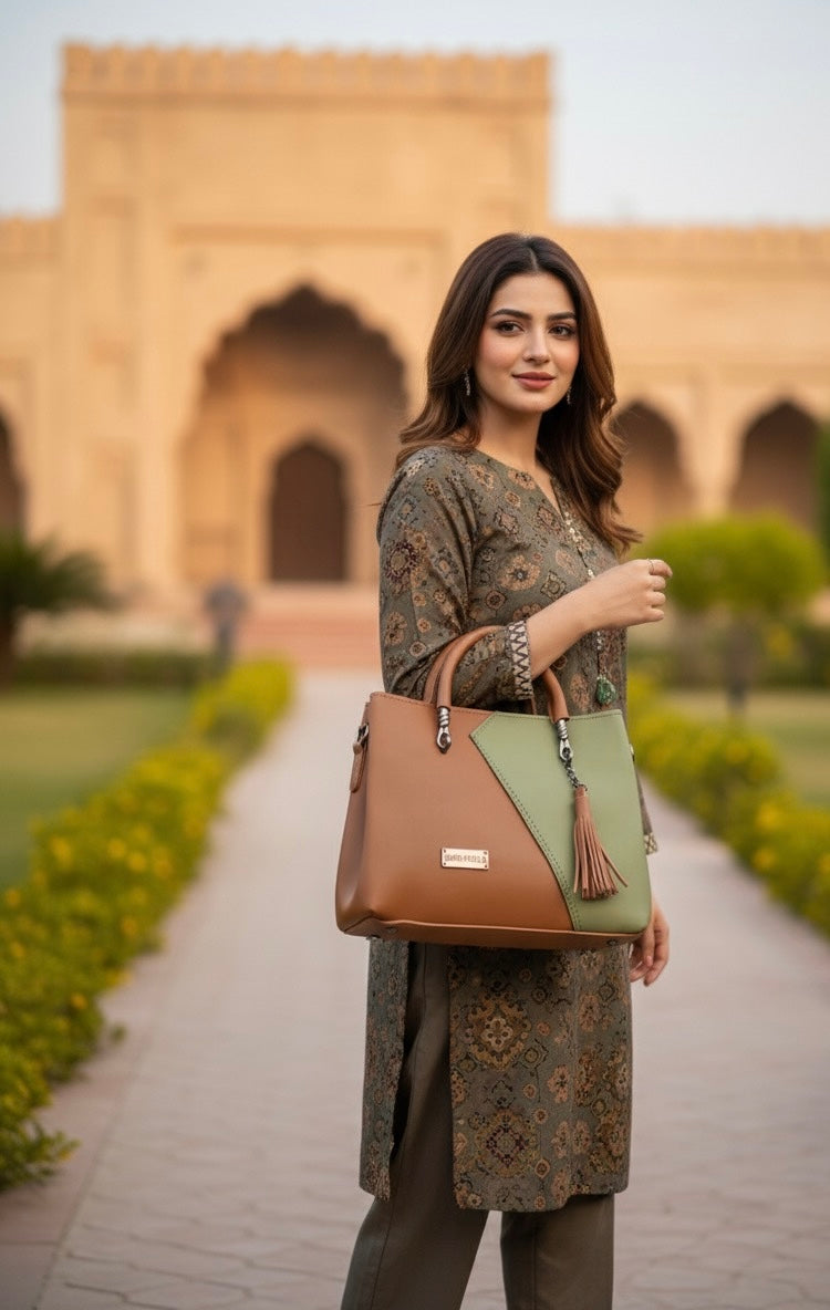 top-handle handbag with a distinctive two-tone color block design and a tassel charm accent 💼