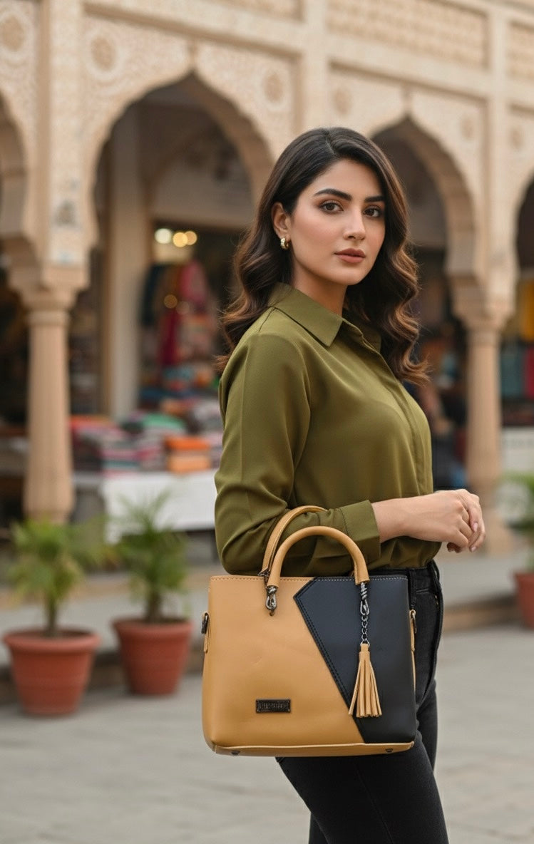 top-handle handbag with a distinctive two-tone color block design and a tassel charm accent 💼