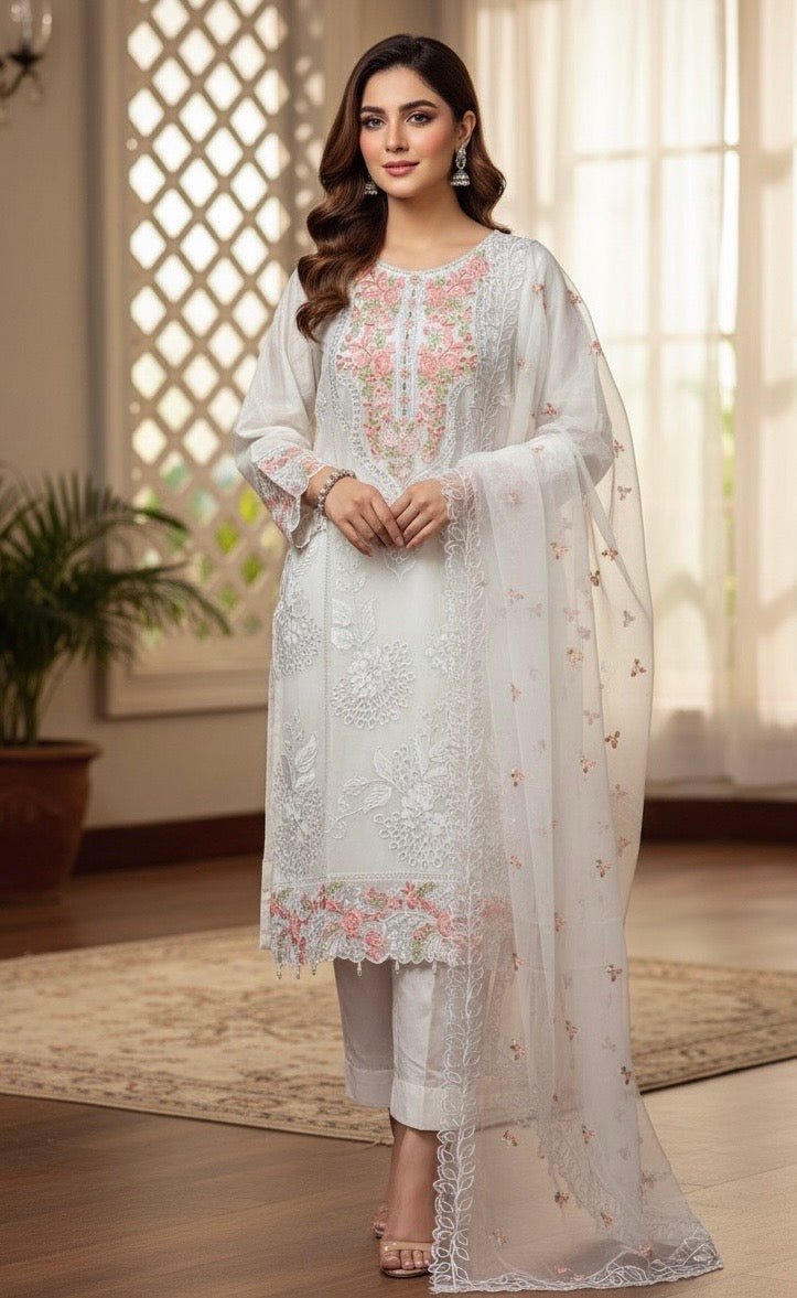 A sophisticated silk-blend suit featuring intricate tone-on-tone floral cutwork and contrasting bright thread embroidery on the neckline and dupatta.